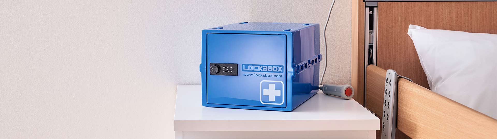 Lockabox One Medi Lockable Medication box on a table next to a hospital bed
