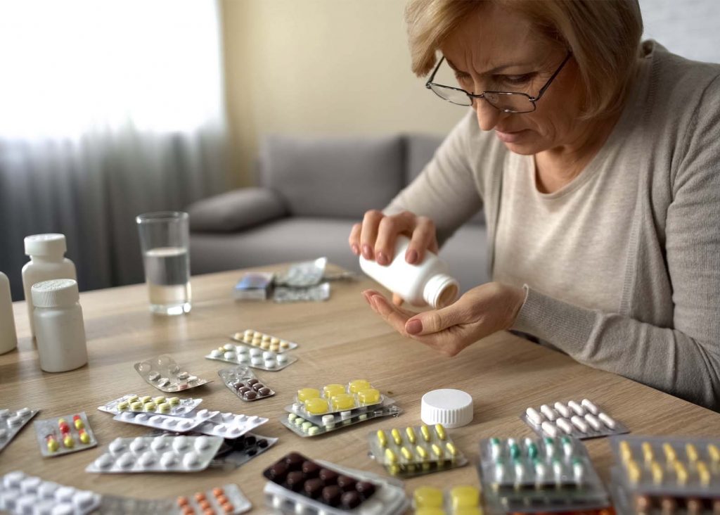 A lady organising her scattered medication on a desks