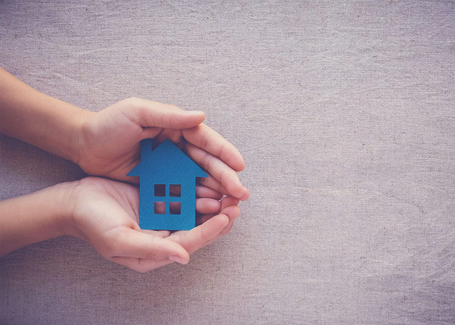 two hands clutching a paper house with love