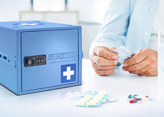 Elderly patient preparing to take medication next to a blue locked medicine box